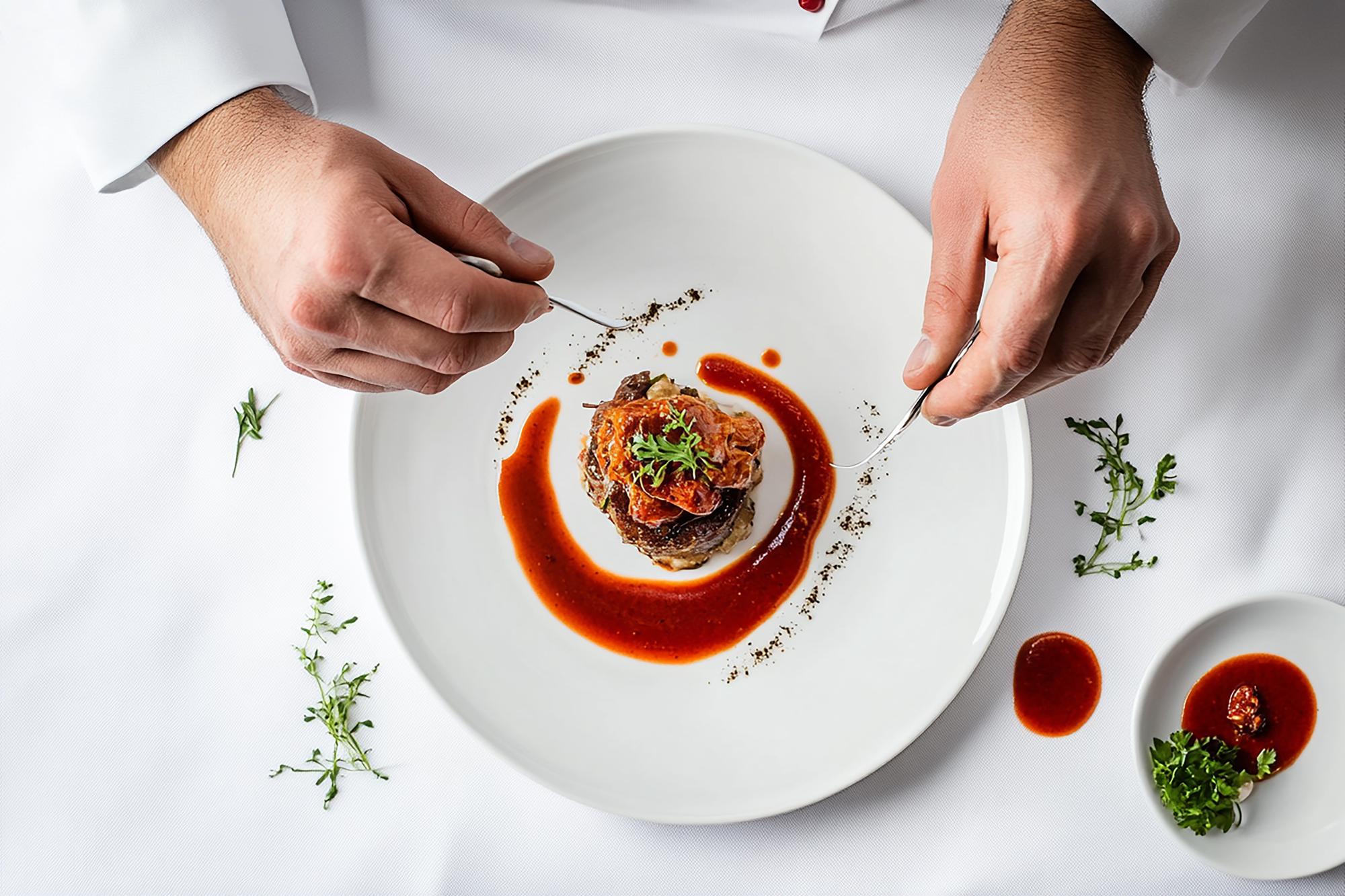 Chef plating a composed dish with tweezers